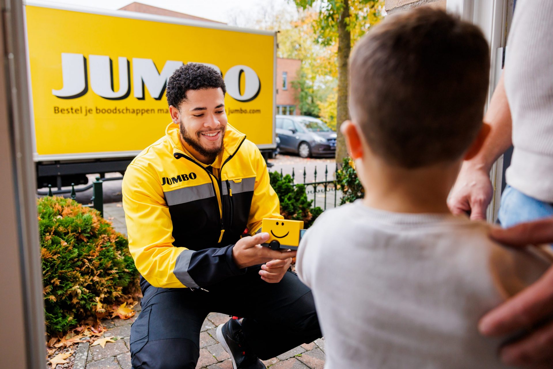Pakketbezorger die glimlachend de bestelling aan een kind aan de deur geeft