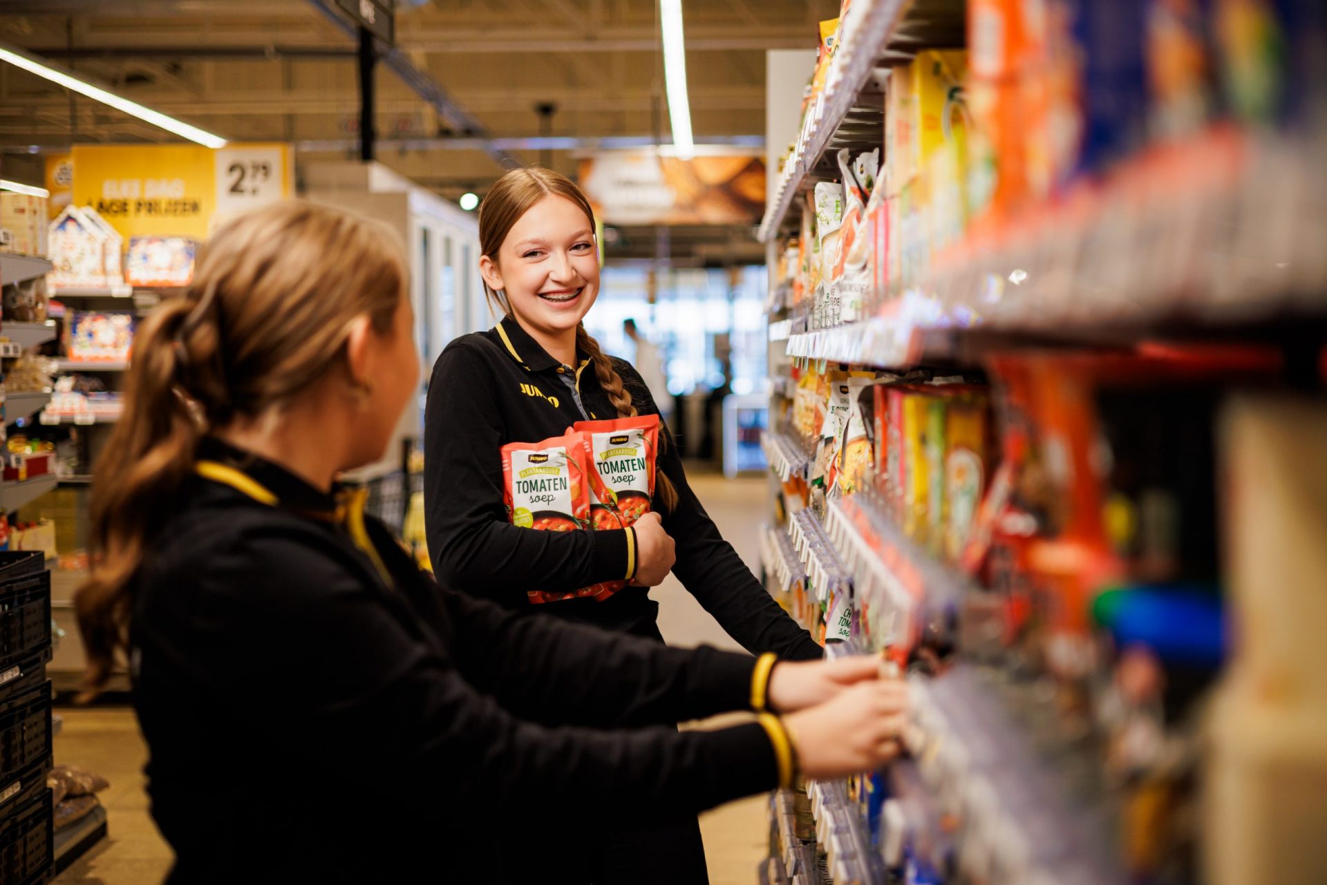 Twee medewerkers zijn lachend de producten aan het spiegelen in de winkel